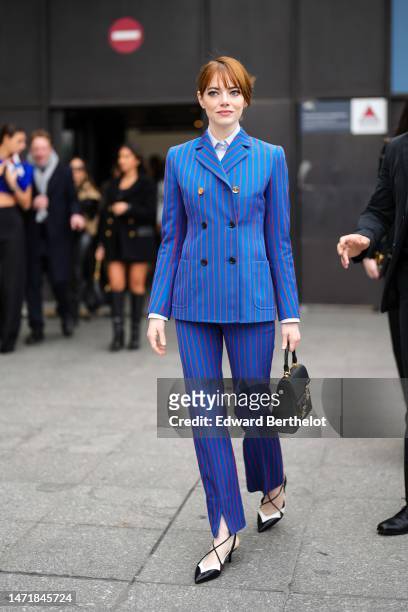 Emma Stone wears a white shirt, a royal blue with small red striped print pattern buttoned blazer jacket, matching royal blue with small red striped...