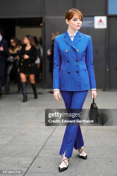 Emma Stone wears a white shirt, a royal blue with small red striped print pattern buttoned blazer jacket, matching royal blue with small red striped...