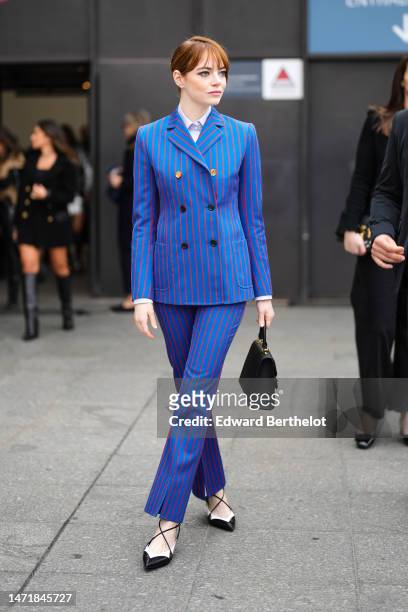 Emma Stone wears a white shirt, a royal blue with small red striped print pattern buttoned blazer jacket, matching royal blue with small red striped...