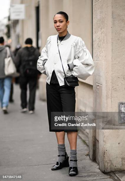 Model is seen wearing a white jacket, black shorts and black shoes with gray socks outside the Rokh show during Paris Fashion Week F/W 2023 on March...