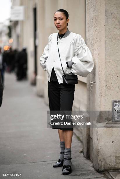 Model is seen wearing a white jacket, black shorts and black shoes with gray socks outside the Rokh show during Paris Fashion Week F/W 2023 on March...