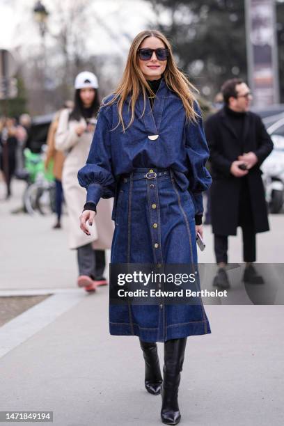 Olivia Palermo wears brown marble print pattern sunglasses, a gold and green large chain necklace, a black ribbed wool turtleneck pullover, a navy...