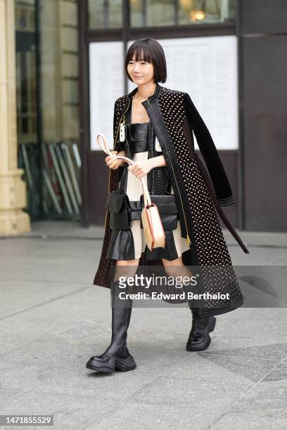 Doona Bae wears a black shiny varnished leather and white latte fabric pattern with a black oversized embroidered zipper shoulder-off / knees dress...