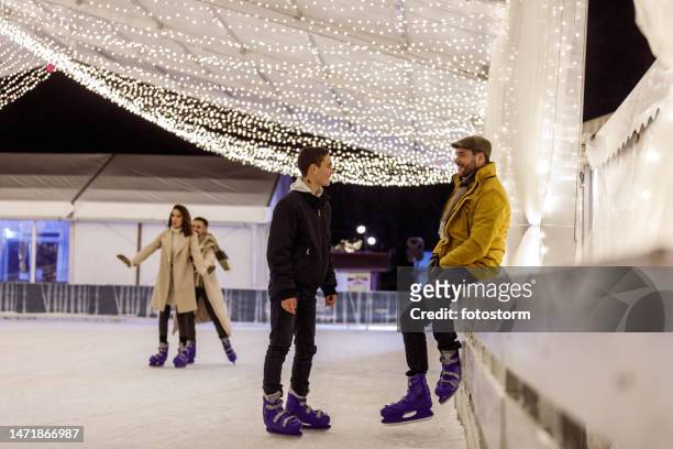 people enjoying a winter's evening and having fun at the ice skating rink - family ice skate stock pictures, royalty-free photos & images