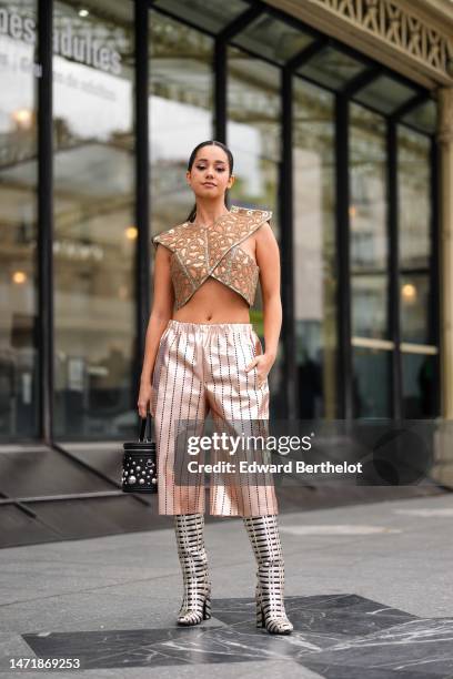 Lena Mahfouf wears a silver with embroidered brown print pattern halter-neck / cropped tank-top from Louis Vuitton, high waist beige gold shiny...