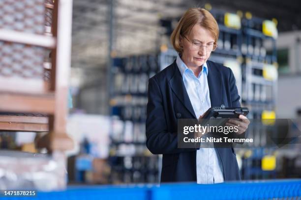 driving the automotive industry forward with complete smart supply chain solutions. a businesswomen or warehouse manager using a tablet computer to check the inventory balance of engineering parts via a mobile app in a factory warehouse. - auditoría fotografías e imágenes de stock