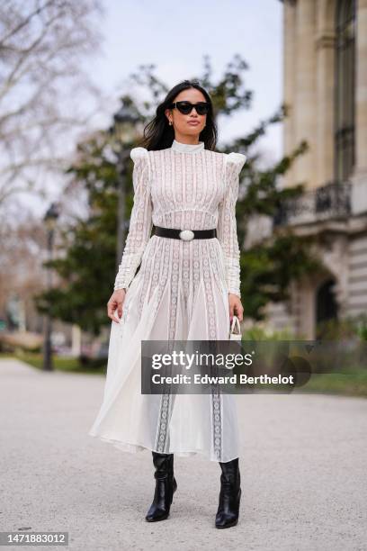 Kelsey Merritt wears a white lace print pattern high neck / shoulder-pads / long sleeves / pleated long dress, a black shiny leather with a white...