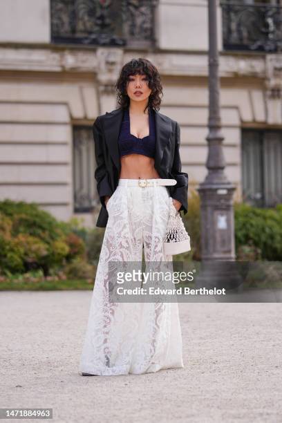 Xiayan wears gold earrings, a navy blue embroidered checkered pattern tweed V-neck / cropped top, a black blazer jacket, a white lace print pattern...