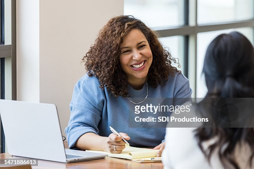 Mature businesswoman smiles encouragingly at unrecognizable female job applicant