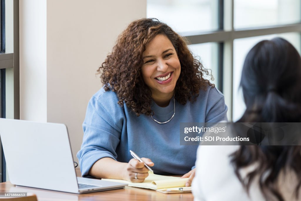 Mature businesswoman smiles encouragingly at unrecognizable female job applicant