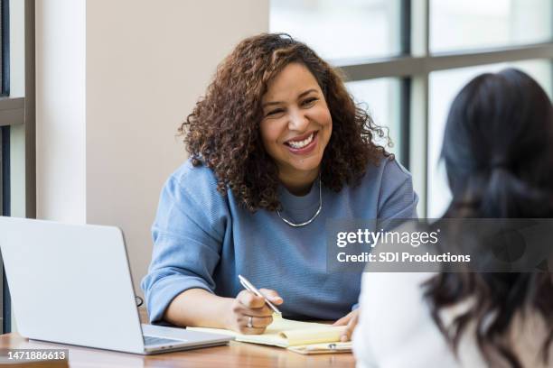 mature businesswoman smiles encouragingly at unrecognizable female job applicant - entrevista imagens e fotografias de stock