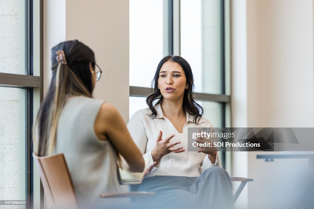 Young adult woman gestures and talks during interview with businesswoman