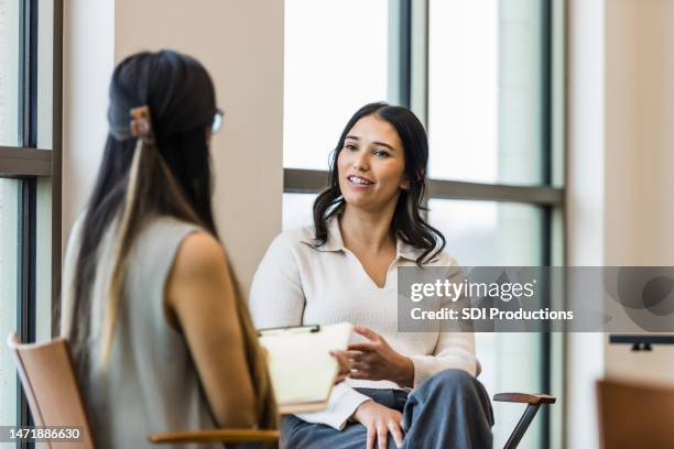 manager irriconoscibile prende appunti durante l'intervista con una giovane donna adulta - psicoterapeuta foto e immagini stock