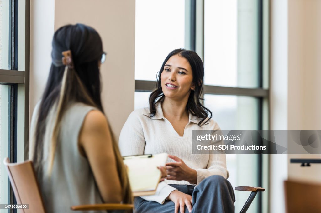 Gerente irreconhecível toma notas durante entrevista com mulher jovem adulta