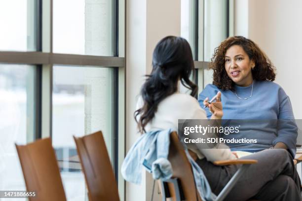 unrecognizable female client listens as female counselor gives advice - health care professional with patient stockfoto's en -beelden