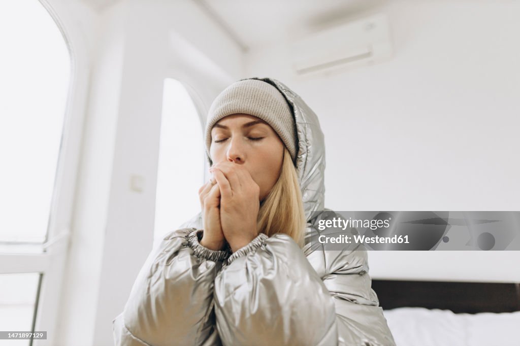 Woman with eyes closed warming hands at home