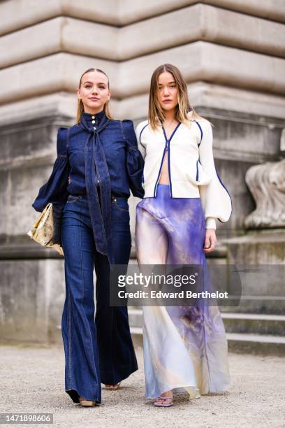 Guest wears gold earrings, a navy blue buttoned high neck denim / long puffy sleeves blouse, matching navy blue denim wide legs pants, a gold shiny...