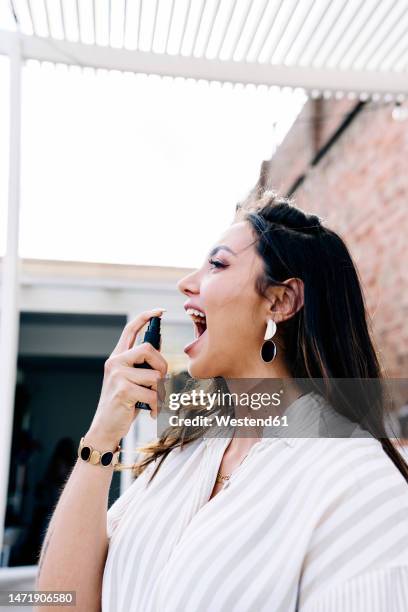 woman using mouth spray on roof - bad breath stock pictures, royalty-free photos & images