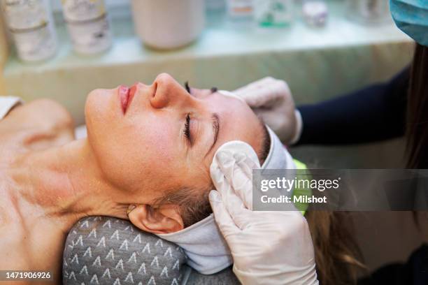 woman getting face treatments at beauty clinic - nursing scrubs stock pictures, royalty-free photos & images