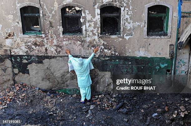 Kashmiri Muslim woman grieves as unseen fire services personnel and volunteers clear debris from the charred remains of the 200-year old shrine of...