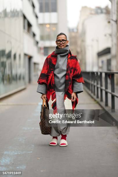 Guest wears black glasses, a pale gray oversized high neck pullover, a black and red print pattern long coat, pale gray puffy pants, a brown LV...