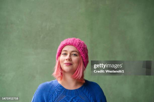 smiling woman with pink dyed hair in front of green wall - pink hair stock pictures, royalty-free photos & images