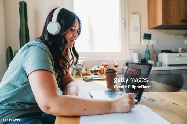 a woman is watching a webinar on her laptop - economy business and finance stock pictures, royalty-free photos & images