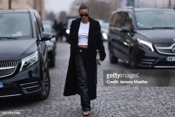 Tamara Kalinic seen wearing a black long coat, white shirt, black leather pants and heels and a black and white bag outside Stella McCartney during...