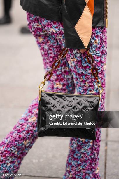 Guest wears a a black / orange / beige shiny leather print pattern zipper jacket from Louis Vuitton, purple / blue / pink / beige embroidered ruffled...