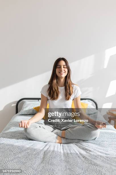 young adult pretty woman meditating on bed. millennial beautiful female doing yoga meditation and breathing exercises in the morning. healthy lifestyle concept - most beautiful female body stock pictures, royalty-free photos & images