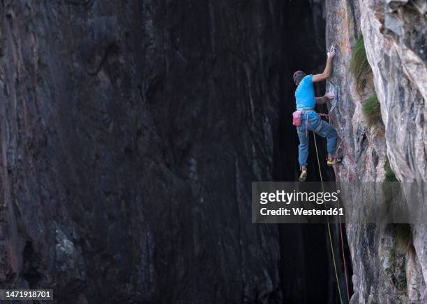 man with harness climbing rocky mountain - safety equipment stock pictures, royalty-free photos & images
