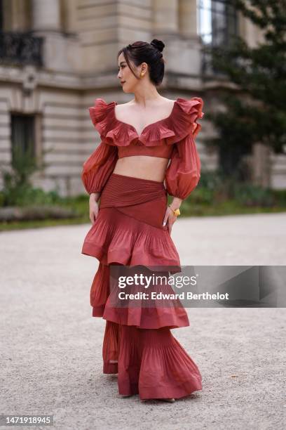 Guest wears gold earrings, a red and burgundy ruffled silk V-neck / puffy long sleeves cropped top, a matching red burgundy ruffled long skirt, a...