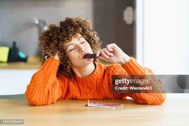 woman with eyes closed enjoying chocolate at home - chocolate eating ストックフォトと画像