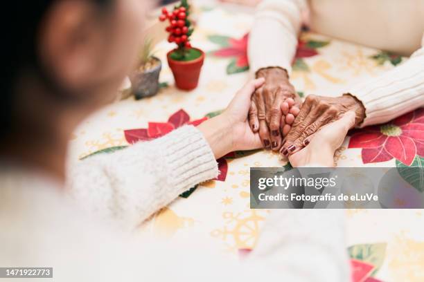 unrecognizable cropped image of woman holding hands with her mother - kin in de hand stock-fotos und bilder