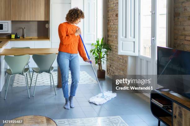 woman with mop cleaning on floor at home - mopping stock-fotos und bilder