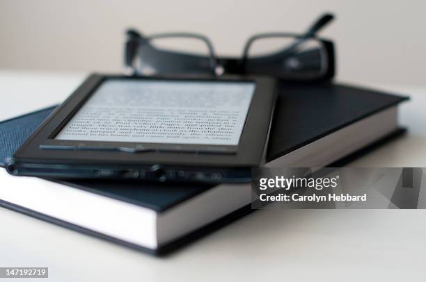 e-reader and book with reading glasses - e reader stock-fotos und bilder