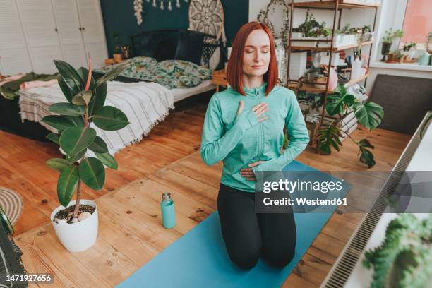 woman with eyes closed meditating on exercise mat at home - woman breathe stock pictures, royalty-free photos & images