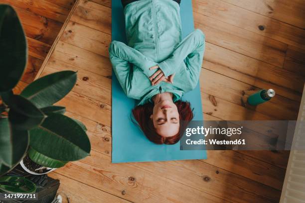 woman doing meditation with hands on chest lying at home - manos sobre el pecho fotografías e imágenes de stock