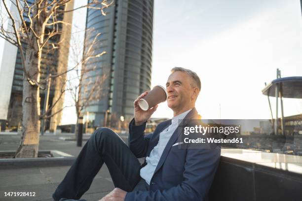 smiling businessman with coffee cup sitting at office park - coffee cup disposable stock pictures, royalty-free photos & images