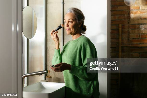 woman doing make-up with brush at home - untar fotografías e imágenes de stock