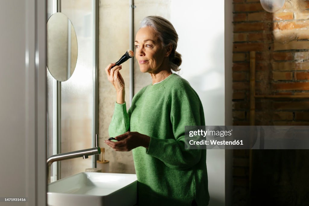 Woman doing make-up with brush at home