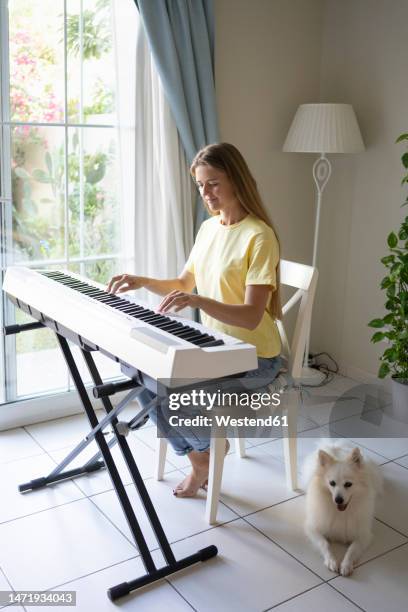 woman playing piano with dog at home - electric piano stock pictures, royalty-free photos & images