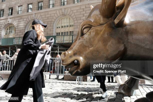 People walk by Wall Street Bull in the Financial District on March 07, 2023 in New York City. Stocks fell in early trading on Tuesday after comments...