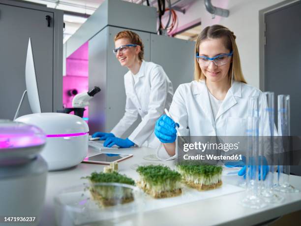 smiling women wearing lab coat working in laboratory - botanist stock pictures, royalty-free photos & images