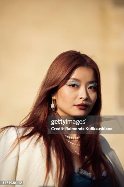 Caroline Hu is seen wearing a cream jacket, blue bralette, blue pearl jeans and white and gold chain Givenchy bag outside the Givenchy show during...