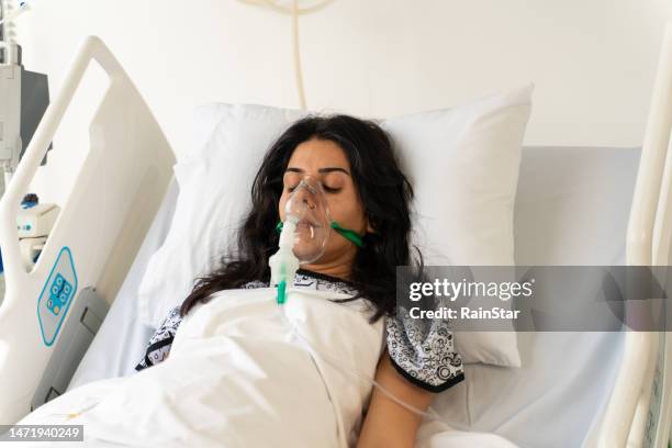 woman with ventilator mask on hospital bed - hospital ventilator stock pictures, royalty-free photos & images