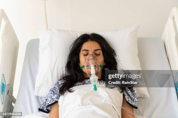 woman with ventilator mask on hospital bed - hospital ventilator stock pictures, royalty-free photos & images