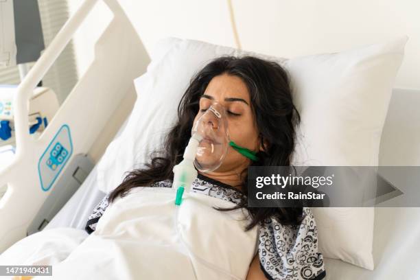 woman with ventilator mask on hospital bed - zichtbare adem stockfoto's en -beelden