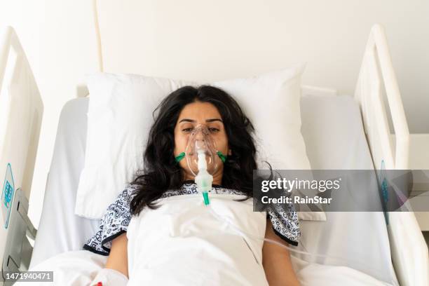 woman with ventilator mask on hospital bed - hospital ventilator stock pictures, royalty-free photos & images