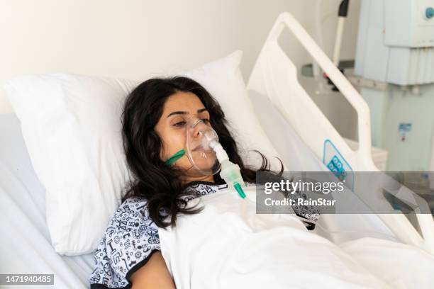 woman with ventilator mask on hospital bed - hospital ventilator stock pictures, royalty-free photos & images